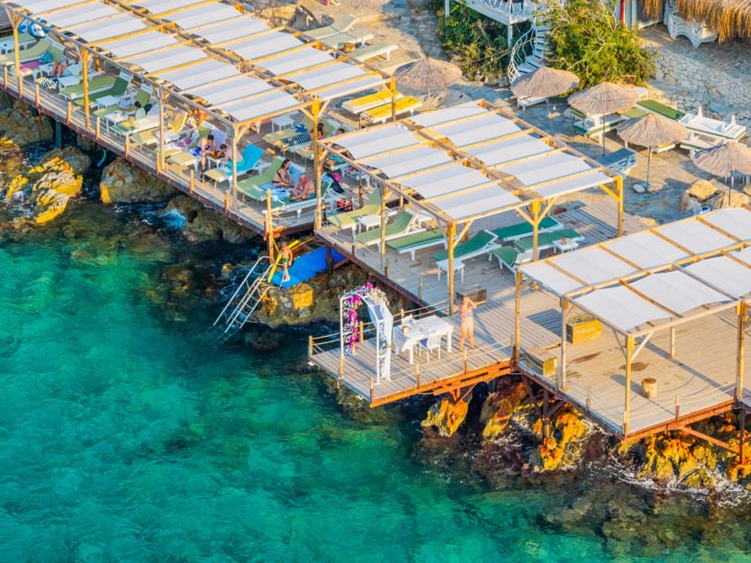 Timber sun decks above clear turquoise water, seen from the air