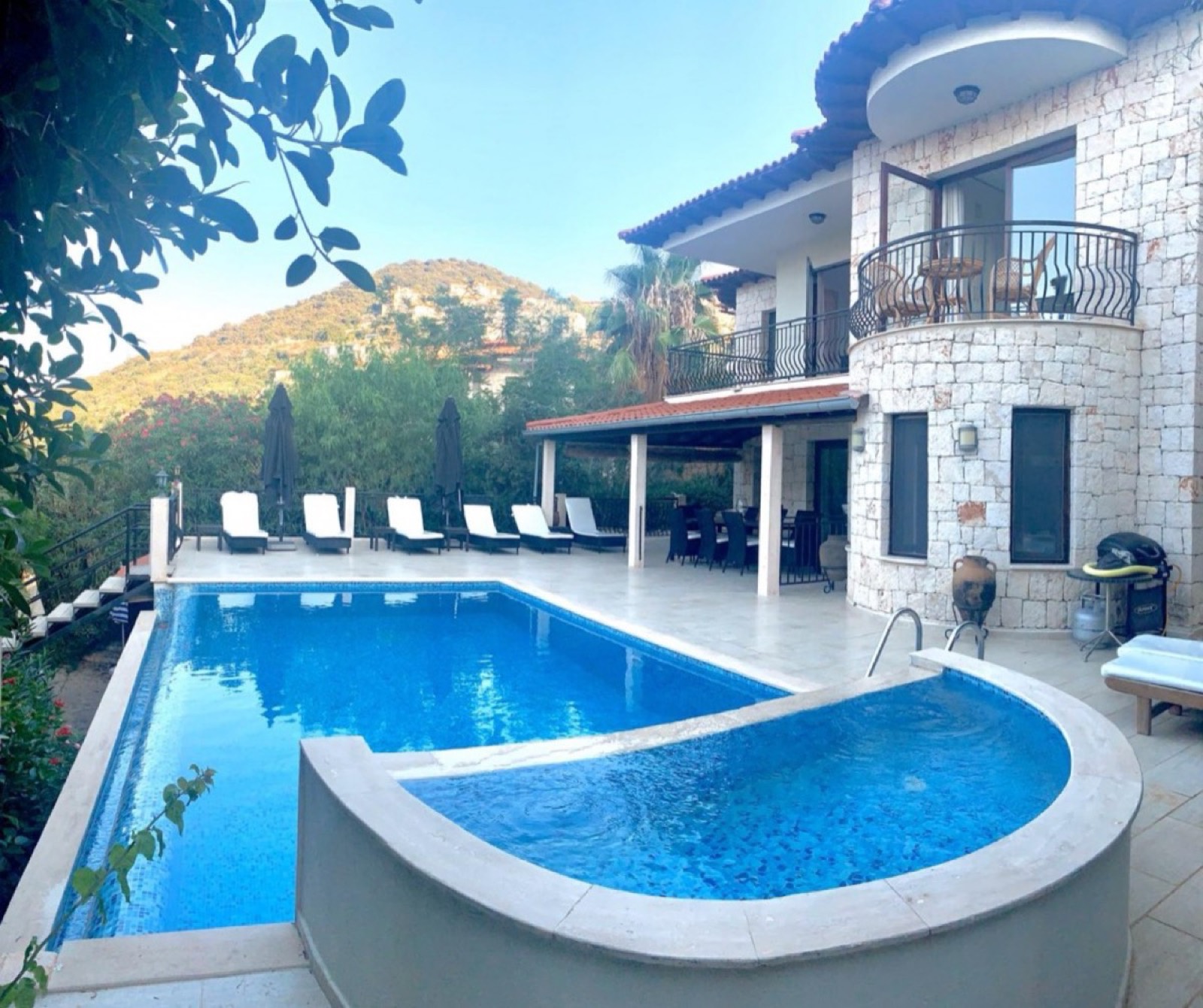 A stone villa with a private pool and sun loungers